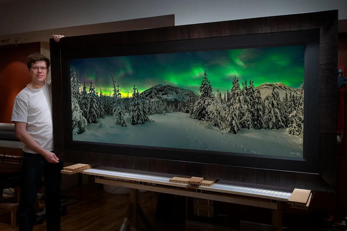 Alex Gubski next to a large format aurora photo print