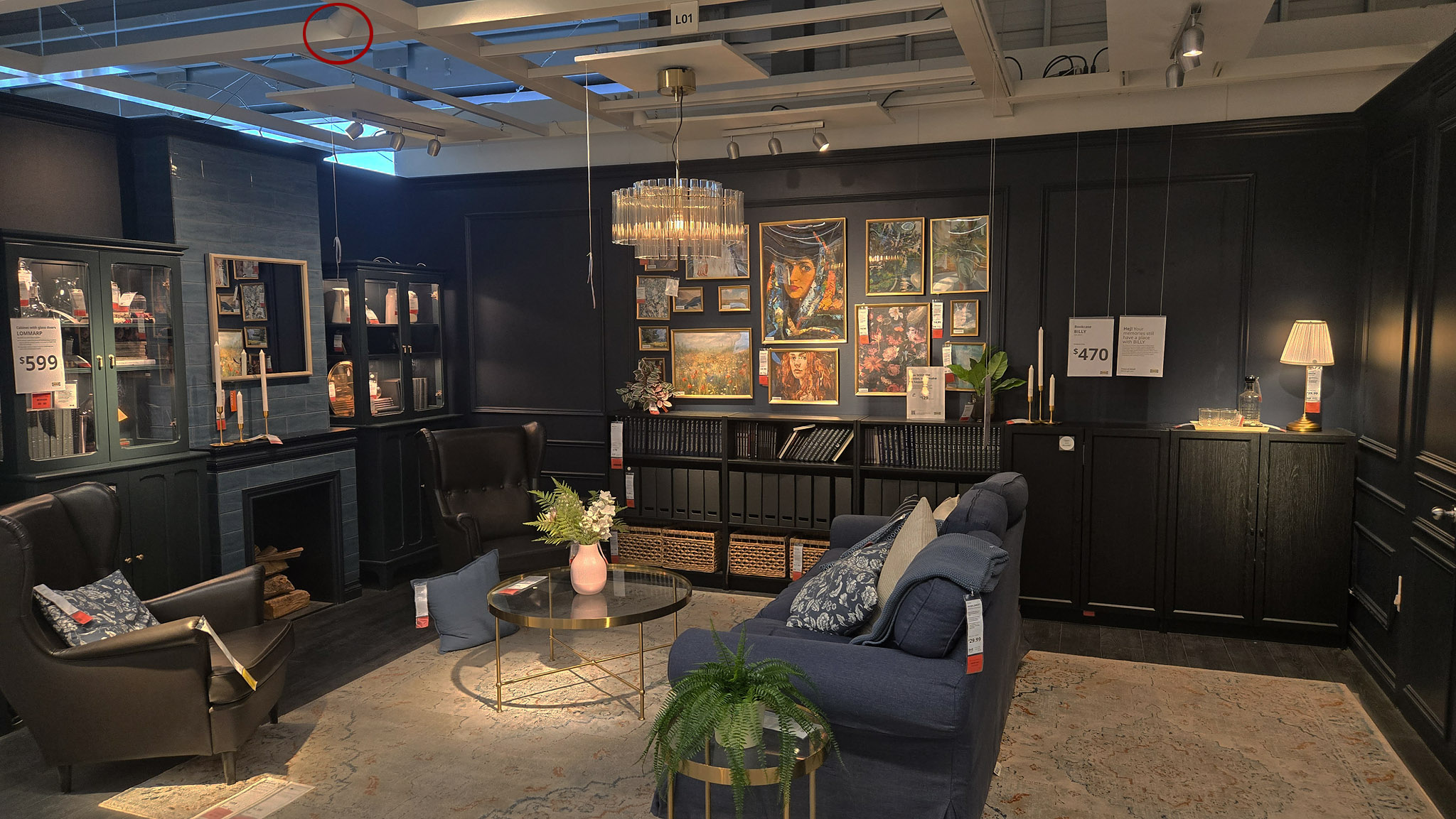 Dark moody IKEA library and gallery-wall vignette with framed art, a crystal chandelier, and a single spotlight circled in red on the far ceiling grid